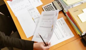 A person sitting at a desk, looking at company papers with numbers and statistics