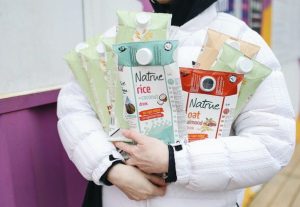 a woman recycling cartons of plant milk